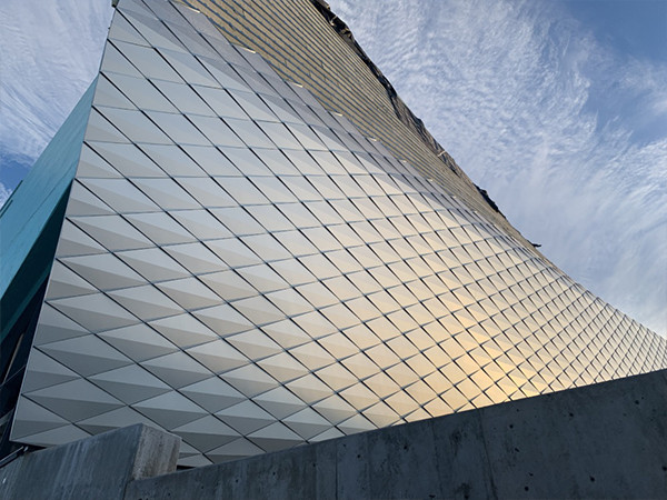 A building exterior with countless diamond-shaped folded aluminum panel cladding.