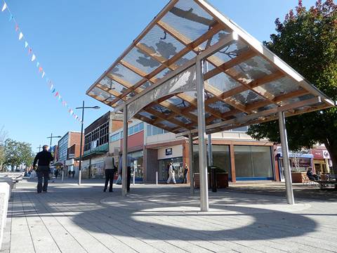 A sheet of perforated sunshade panel with  special patterns is set up a shed in the street.