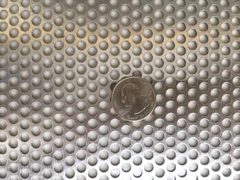 A piece of galvanized round hole perforated sheet with a metal coin on its surface.