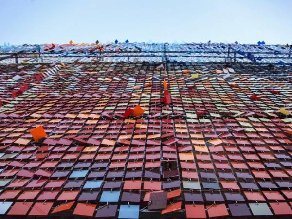 A building facade adorned with numerous dark coloured acrylic perforated kinetic panels