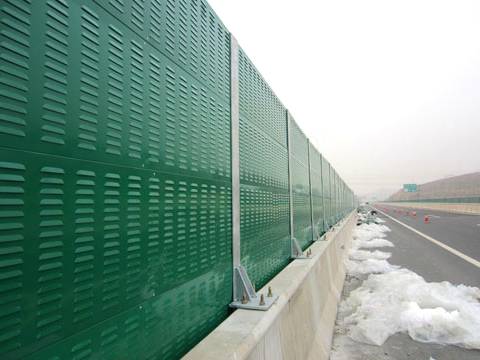 Green common shape noise barriers are installed on the highway.