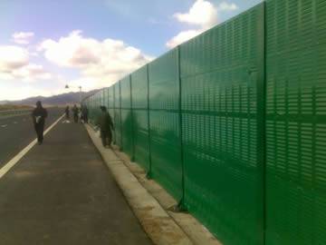 Green noise barriers are installed on the highway.