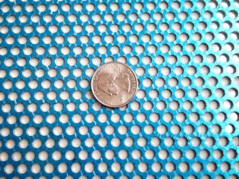 A piece of perforated steel sheet with blue protecting layer and a metal coin on its surface.